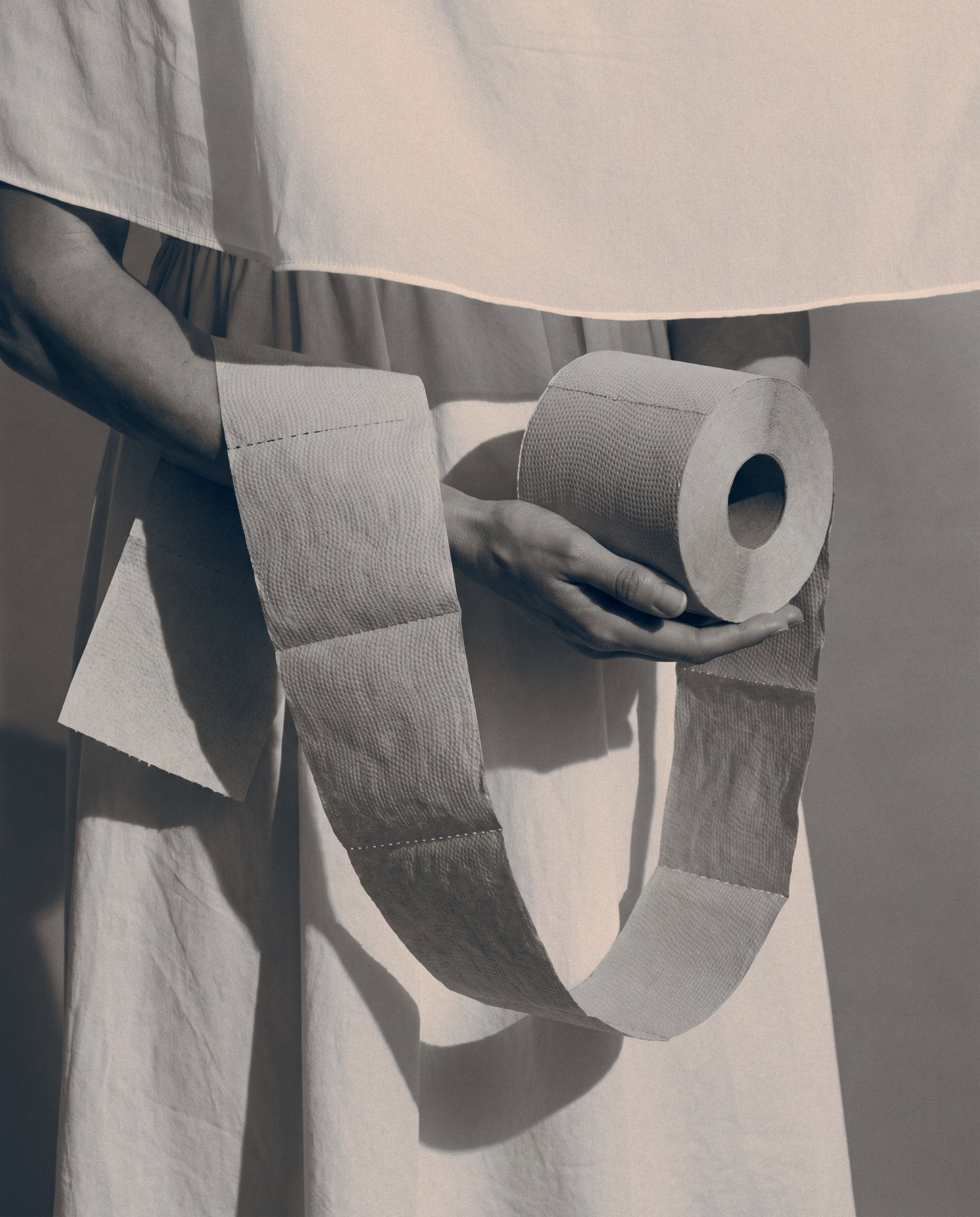 BAMBUM roll held in crossed arms beside woman in cream linen, natural setting